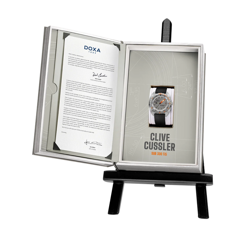 1. DOXA SUB 300 Ti5 Clive Cussler watch presented in its open special-edition display packaging with accompanying documentation.