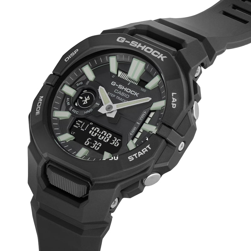 Angled close-up of a black Casio G-SHOCK ana-digi watch featuring green luminous hour markers, silver hands, Bluetooth connectivity, digital display and black resin strap.