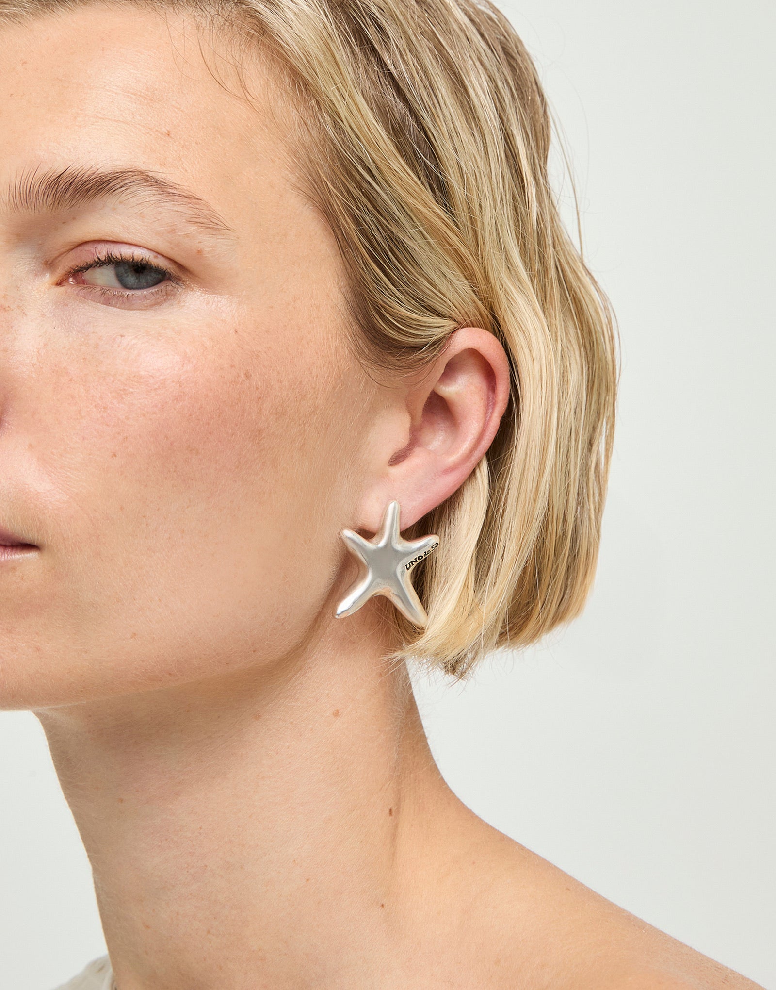 UNOde50 silver plated starfish stud earrings with polished organic starfish design, front view.