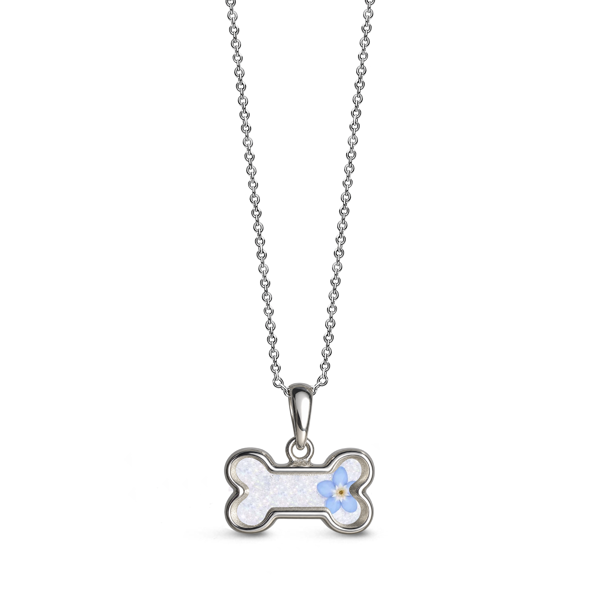 Sterling silver dog bone-shaped ashes keepsake pendant necklace featuring a forget-me-not flower with a white glitter memorial setting with incorporated ashes and a polished silver border.