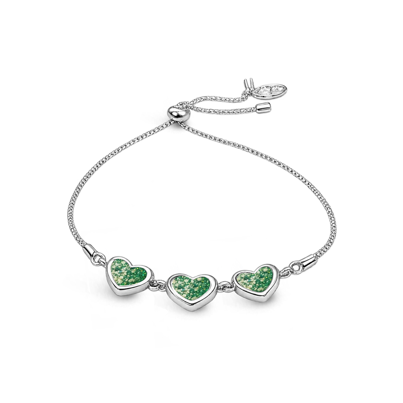 Sterling silver three-heart ashes keepsake bracelet featuring green glitter memorial settings with incorporated ashes and an adjustable slider fastening.
