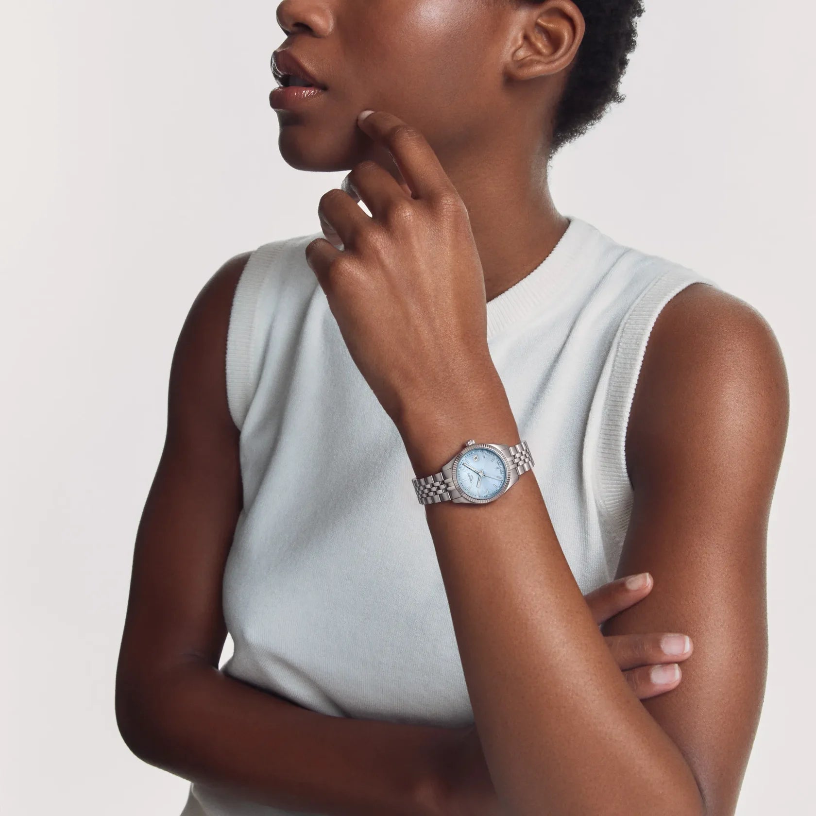 Tissot stainless steel watch with ice blue dial and fluted bezel worn on the wrist.